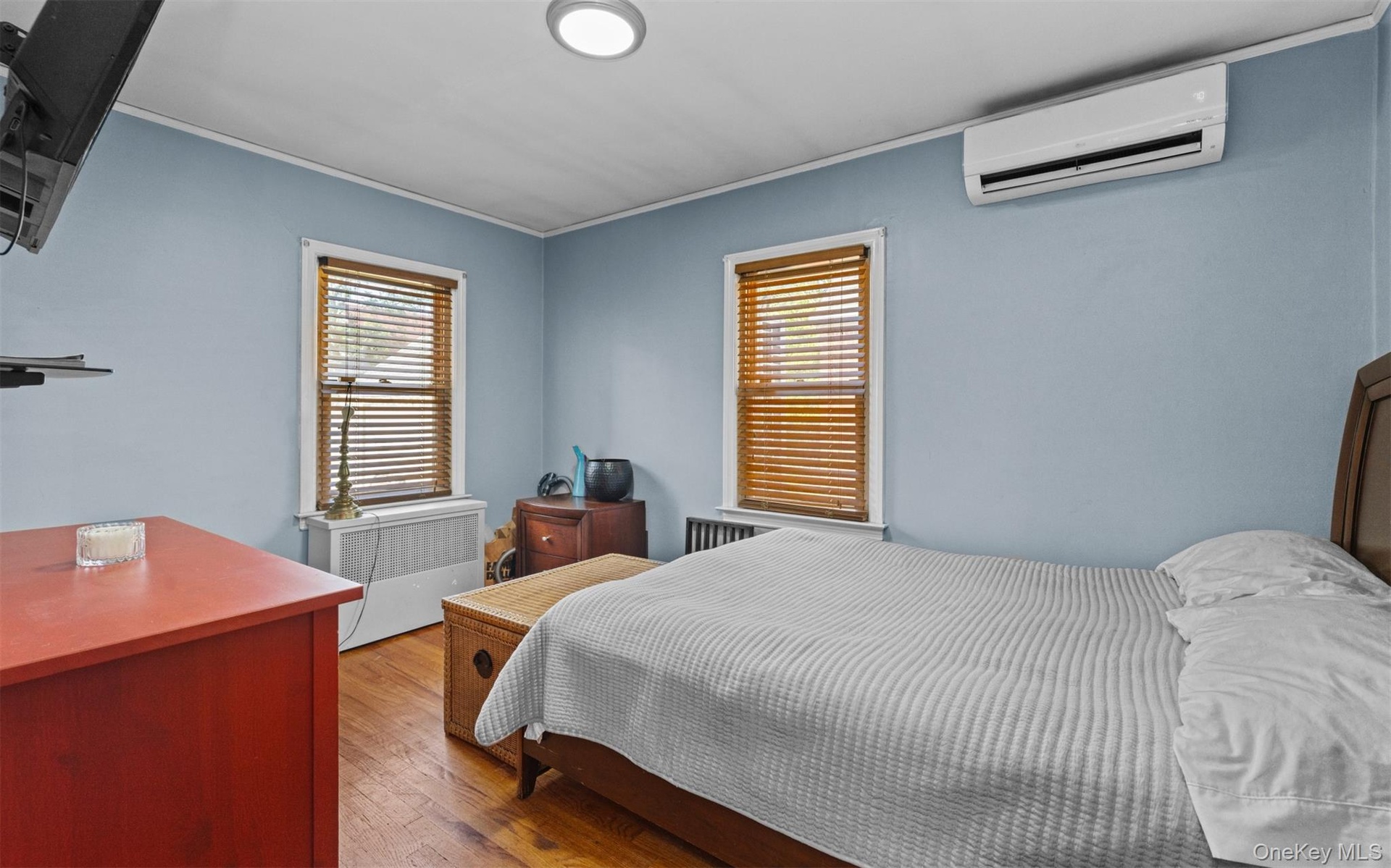 Bedroom with wood finished floors, a wall mounted AC, and crown molding