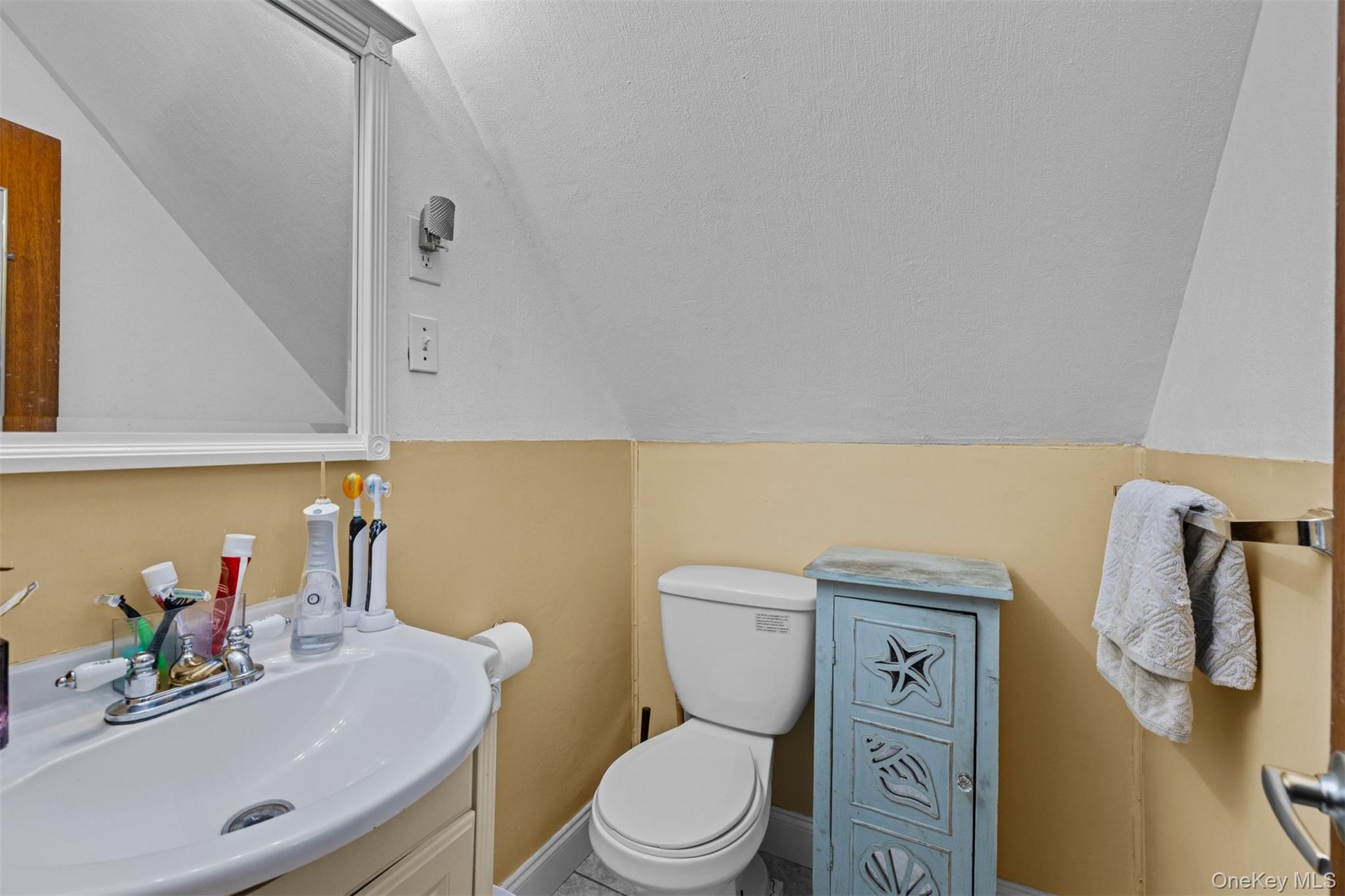 Half bathroom with vanity and vaulted ceiling