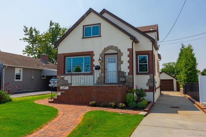 View of front of house with brick siding, an outbuilding, stucco siding, and a garage