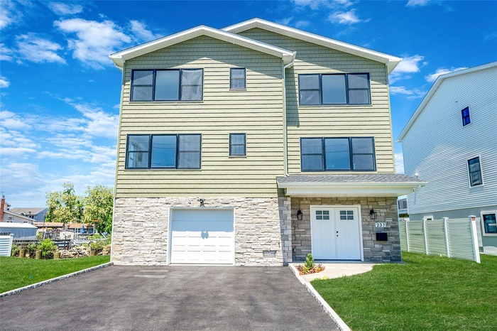 View of front of property featuring stone siding, driveway, and a garage