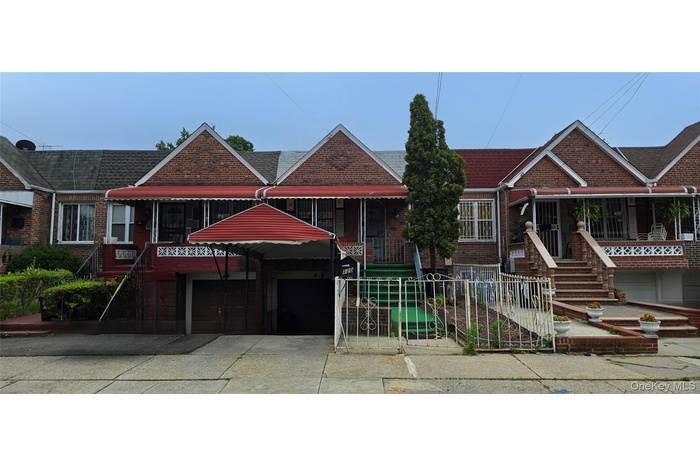 View of front of property with a garage, driveway, brick siding, and a shingled roof