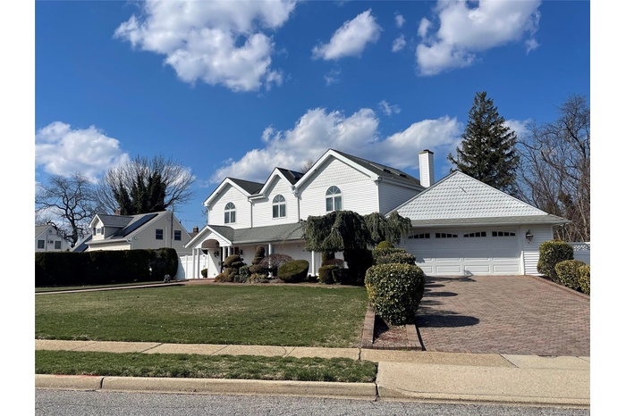 Traditional home featuring decorative driveway, a chimney, a front lawn, and a garage