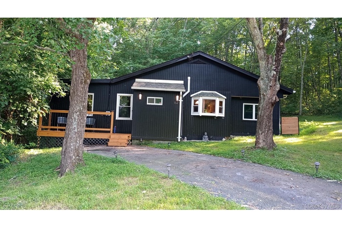 View of front facade with a wooden deck and a front lawn