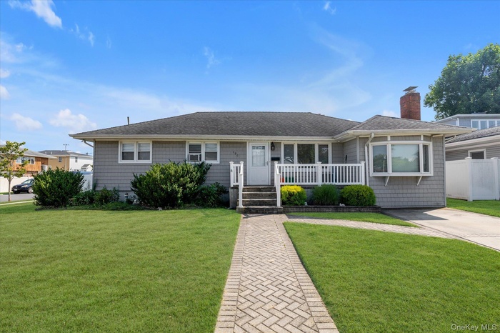 Ranch-style house with a shingled roof, a front yard, and a chimney