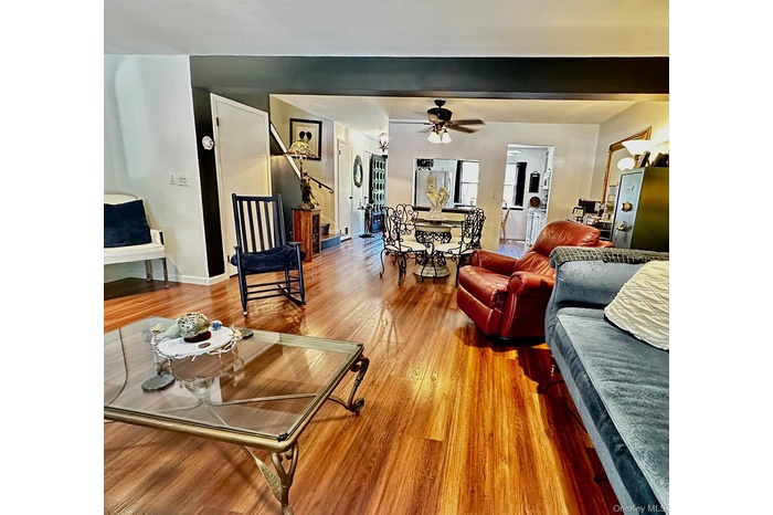 Entering from the assigned parking behind the unit - Living room featuring light wood-type flooring, ceiling fan, and stairs