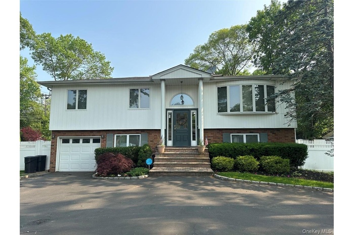 Bi-level home featuring brick siding, a garage, and asphalt driveway