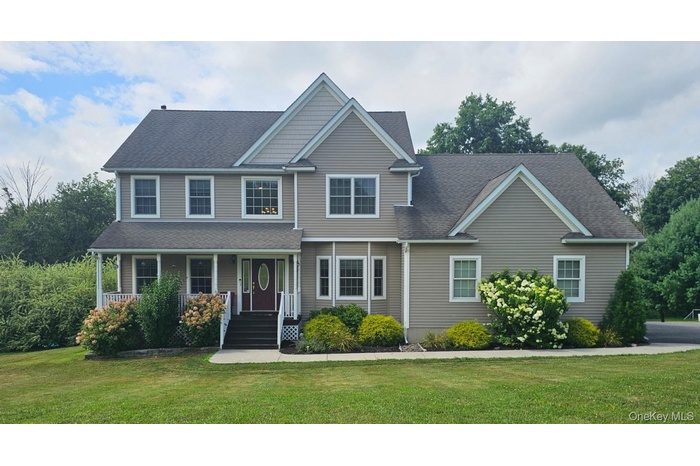 View of front of house with a front lawn, a porch, and a shingled roof