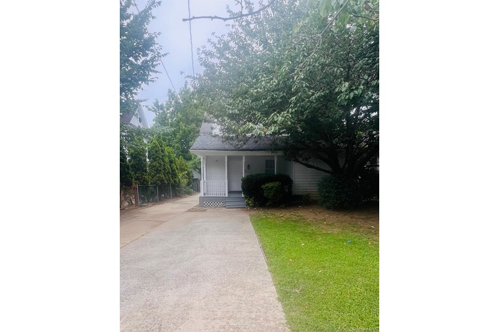 View of front facade featuring covered porch, concrete driveway, and a shingled roof