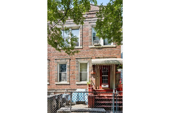 View of front of home featuring a fenced front yard, brick siding, covered porch, and a gate
