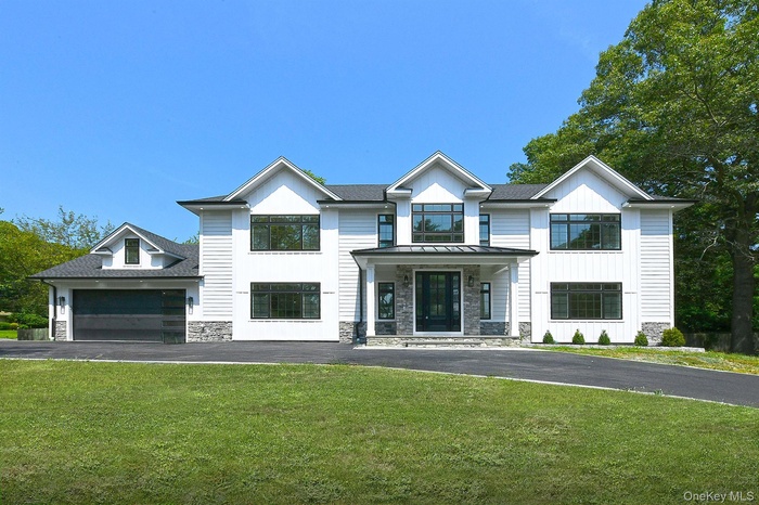 Blending Contemporay and Traditional featuring stone siding, a front yard, covered porch, and a garage