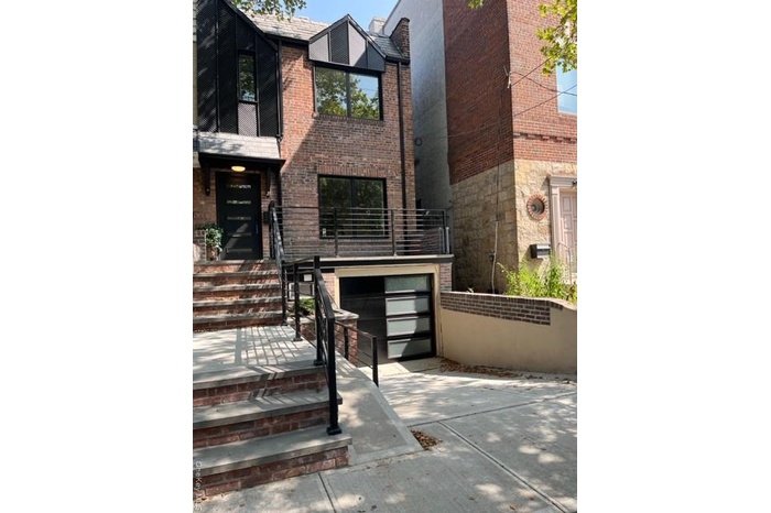 Entrance to property featuring brick siding, concrete driveway, and an attached garage