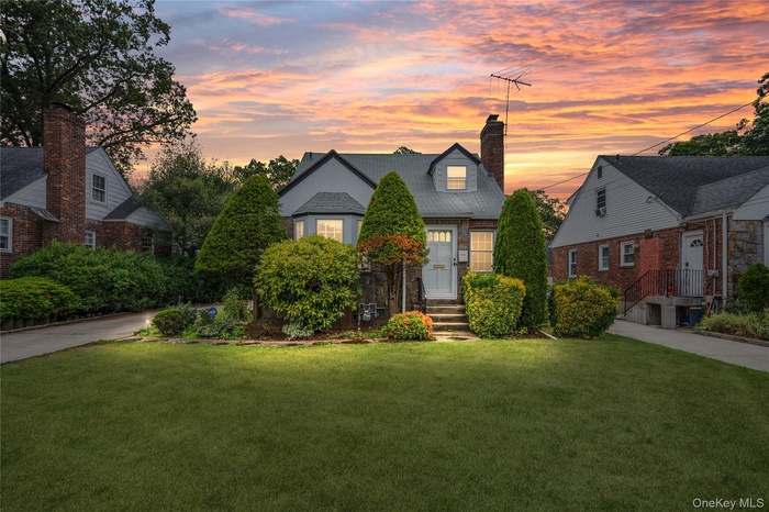 View of front of home featuring a yard, a chimney, brick siding, and entry steps