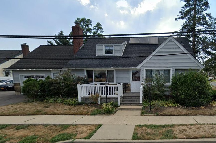 View of front of property with a porch, a chimney, solar panels, and roof with shingles