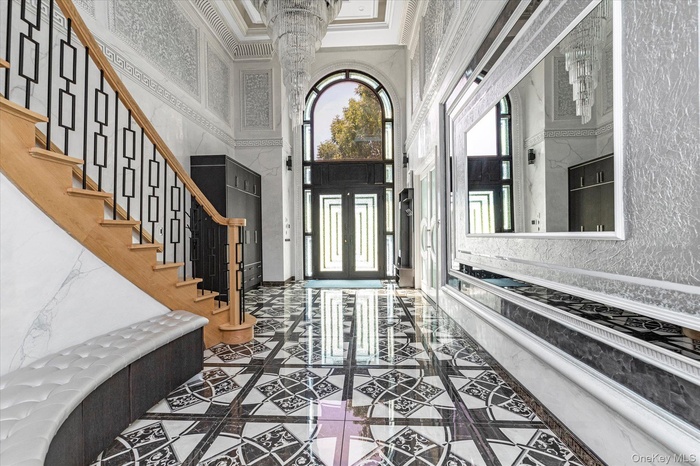Entryway featuring inlaid floor details, a towering ceiling, crown molding, stairway, and decorative columns