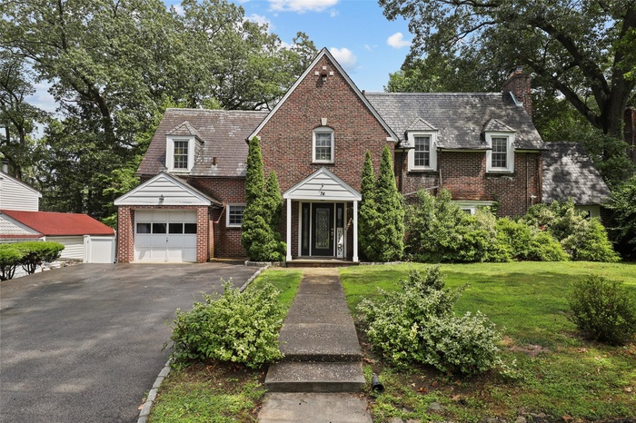 View of front of home with brick siding, a high end roof, and a chimney