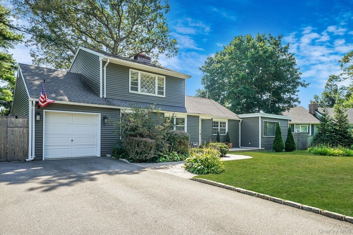 View of front of property with a garage, roof with shingles, driveway, and a chimney