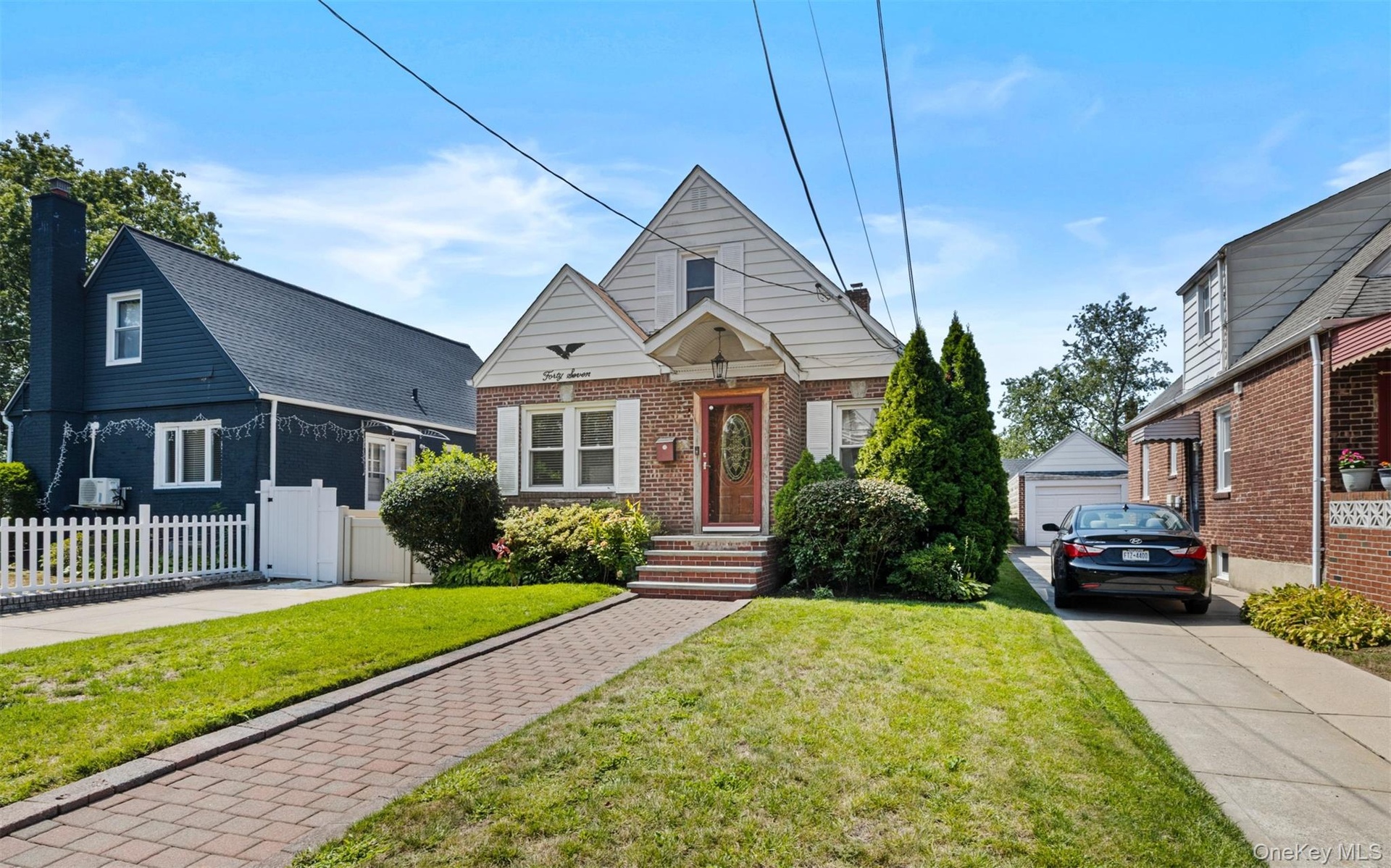 Bungalow-style house featuring an outdoor structure, brick siding, a chimney, and a garage