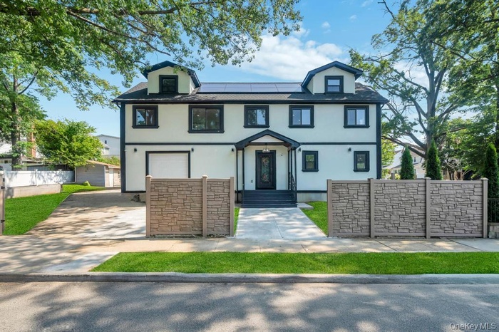 View of front of house featuring stucco siding, roof mounted solar panels, an attached garage, and driveway