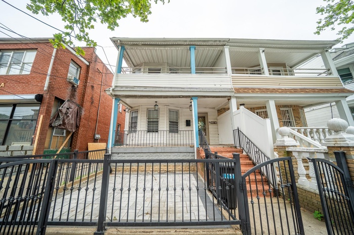 View of front facade featuring a porch, a fenced front yard, a gate, stairs, and a balcony