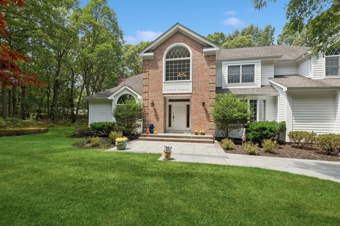 View of front of property featuring a front yard, brick siding, and roof with shingles