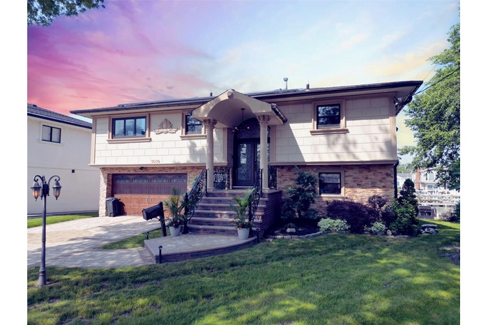 View of front of home with an attached garage, brick siding, a front yard, and concrete driveway