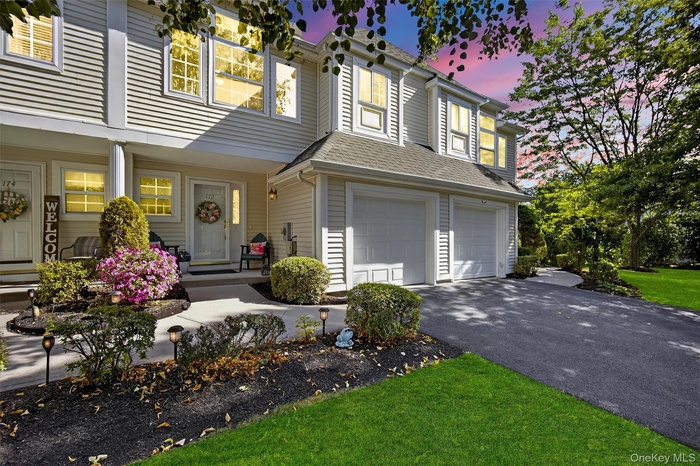 View of front of property with covered porch, an attached garage, asphalt driveway, and roof with shingles