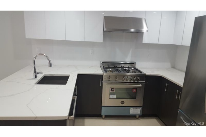 Kitchen with modern cabinets, gas range oven, freestanding refrigerator, and white cabinetry