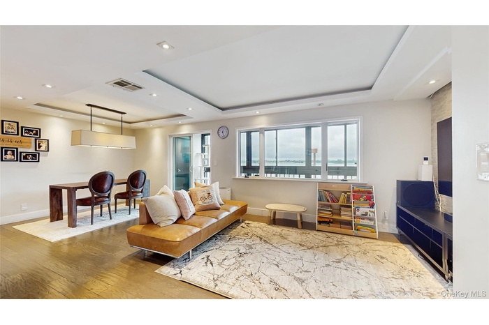 Living area with a tray ceiling, baseboards, wood-type flooring, and recessed lighting