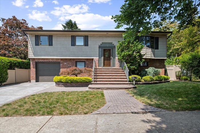 Bi-level home featuring driveway, brick siding, and a garage