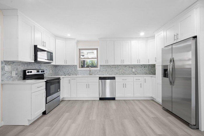 Kitchen featuring a sink, stainless steel appliances, light countertops, and light wood-style flooring