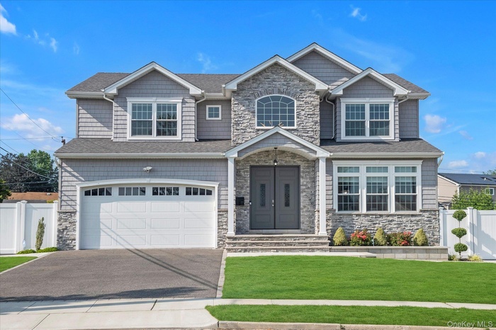 Craftsman-style house with stone siding, asphalt driveway, a garage, and a gate
