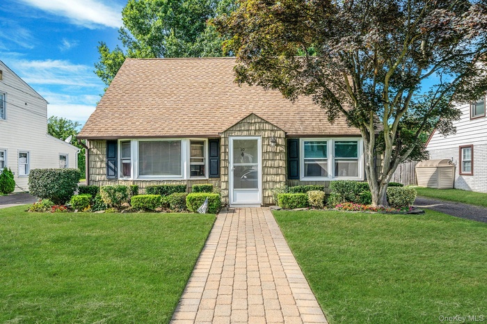 View of front of property with a shingled roof and a front lawn