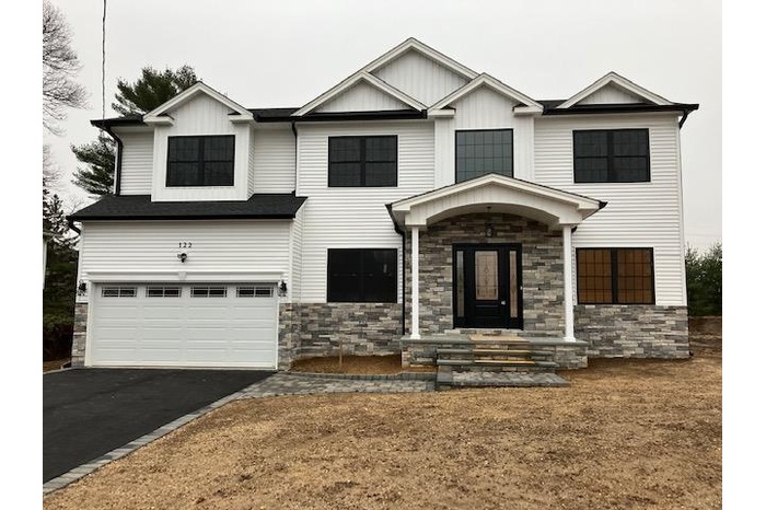 View of front of property with stone siding, a garage, and driveway