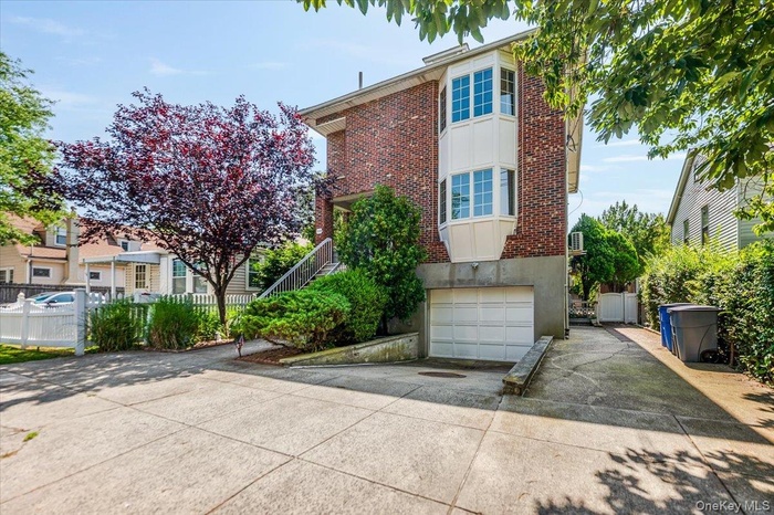 View of front facade with driveway, a garage, and brick siding