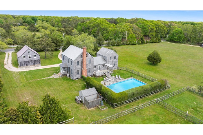 Aerial view of property and surrounding area featuring a pool area and open farm fields