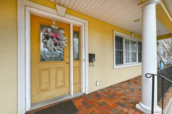View of exterior entry featuring covered porch and stucco siding