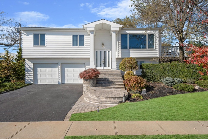 View of front of property with french doors, an attached garage, driveway, and a front yard