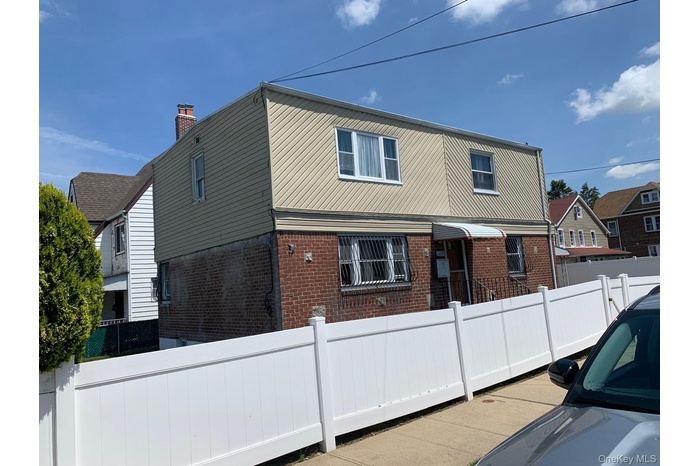 Back of property with brick siding and a fenced front yard