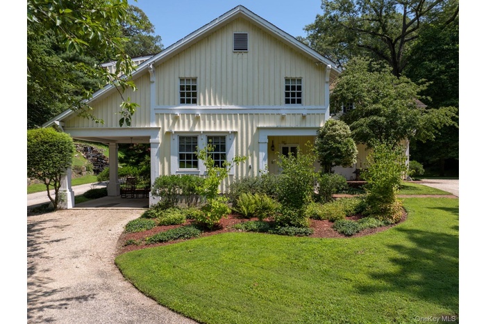 View of front facade with driveway, a front lawn, and board and batten siding