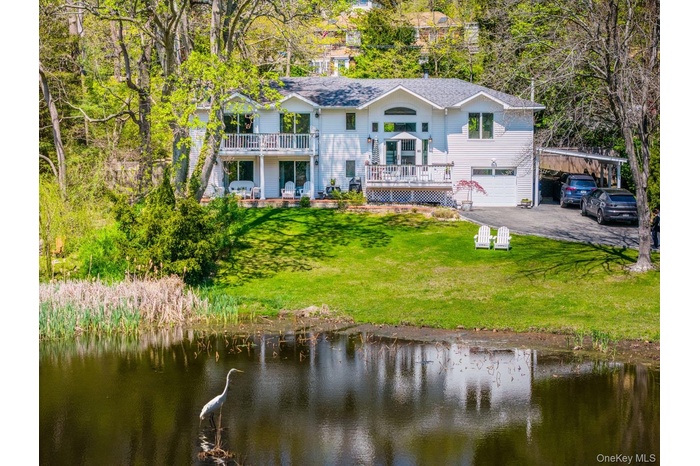 Back of property with a lawn, driveway, a garage, and a water view