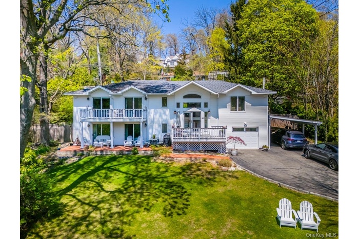 View of front of home with aphalt driveway, a deck, fence, a garage, and a front lawn