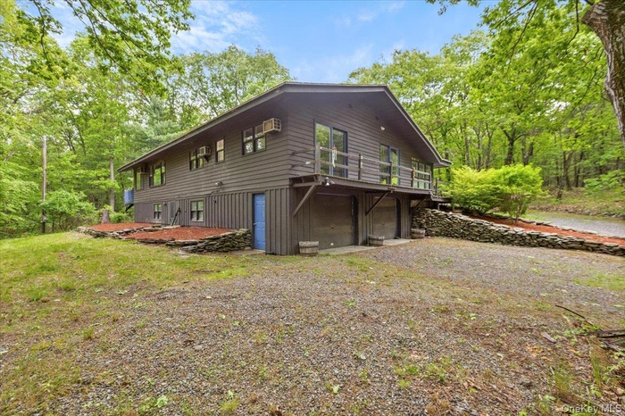 View of home's exterior featuring a garage, gravel driveway, and a deck