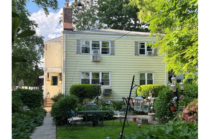 Rear view of house featuring a chimney, a patio area, and a wall mounted air conditioner