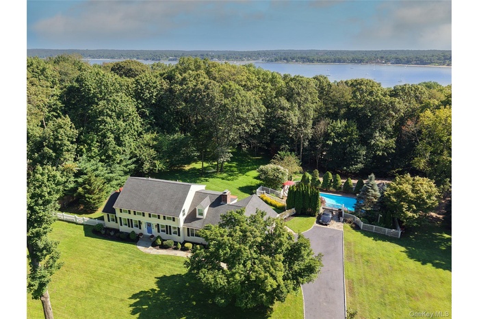 Aerial view of property and surrounding area with a pool and a heavily wooded area