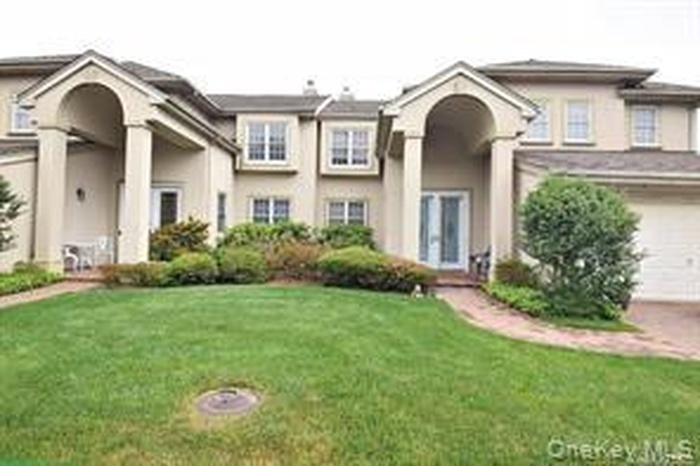 View of front of house featuring a front yard, stucco siding, and a garage