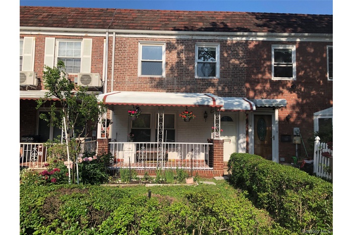 View of front of house featuring brick siding, a porch, and a cooling unit