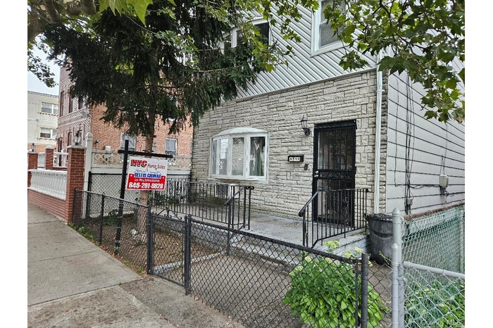 View of front facade featuring a fenced front yard, stone siding, and a gate