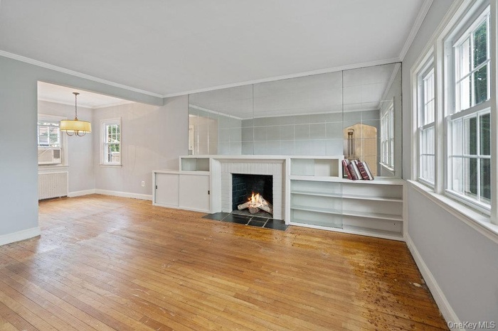 Large living room featuring ornamental molding, hardwood / wood-style floors, a fireplace, and radiator