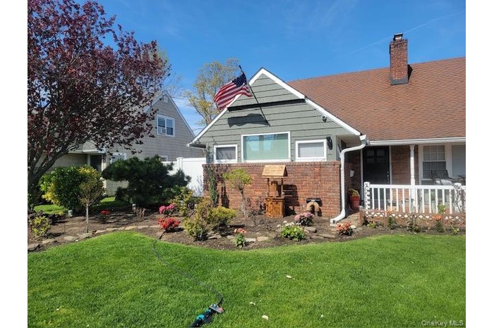 View of front of property featuring brick siding, a front yard, a chimney, a porch, and a shingled roof