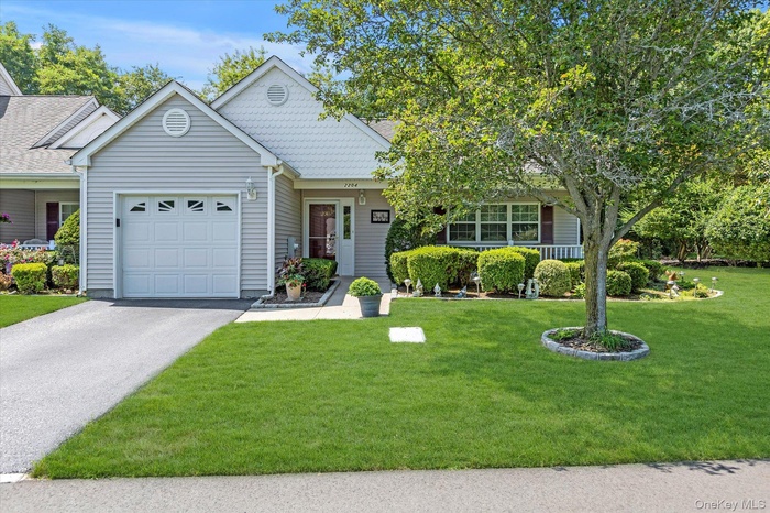 View of front of property featuring a front yard, asphalt driveway, and a garage